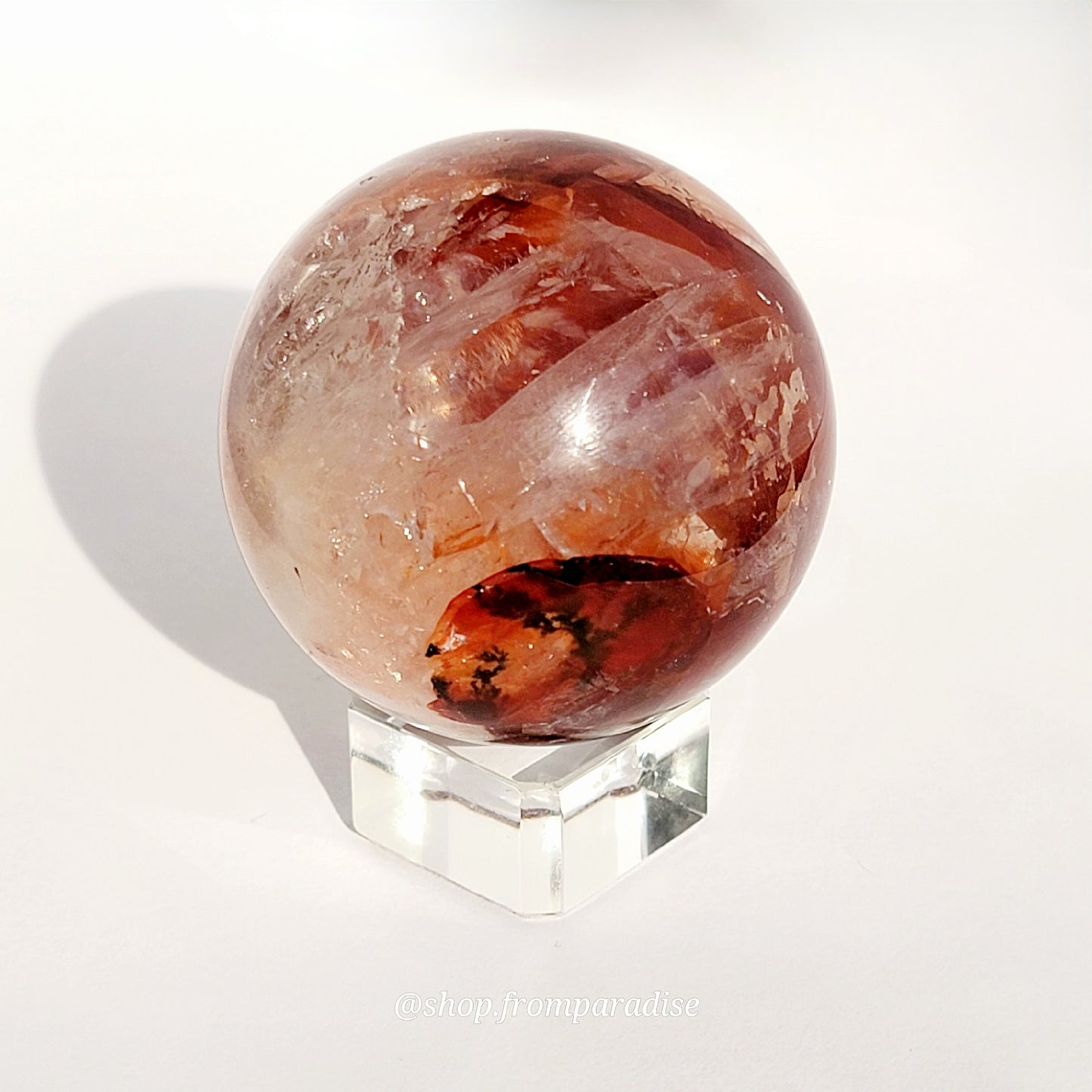 Fire Quartz Red Hematoid Sphere on glass sphere holder against white background
