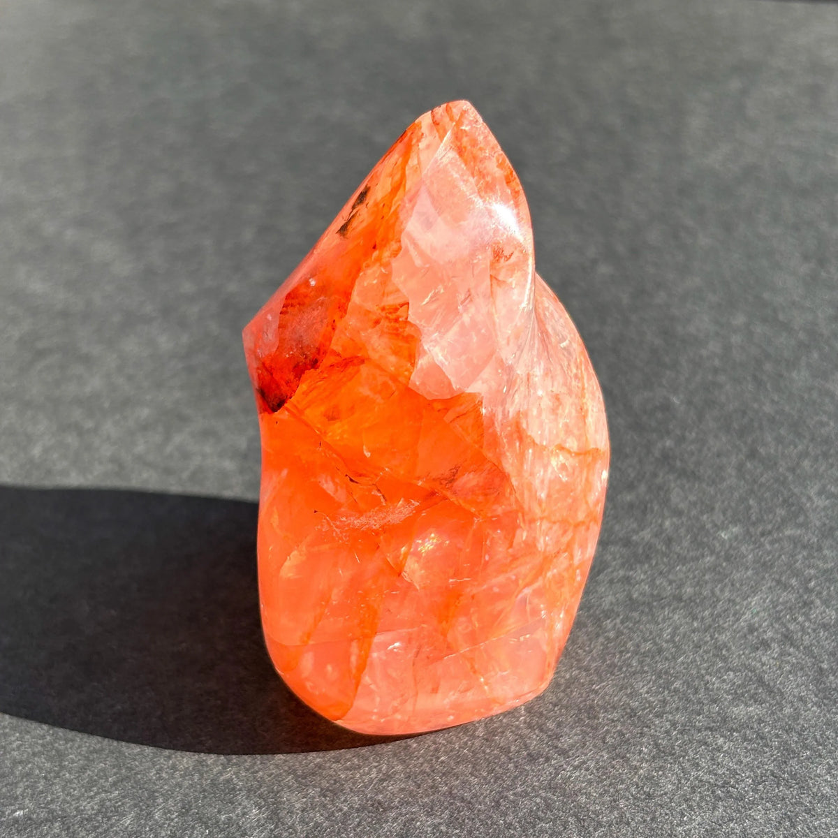 Fire Quartz Red Hematoid Crystal Flame Sculpture against a black background