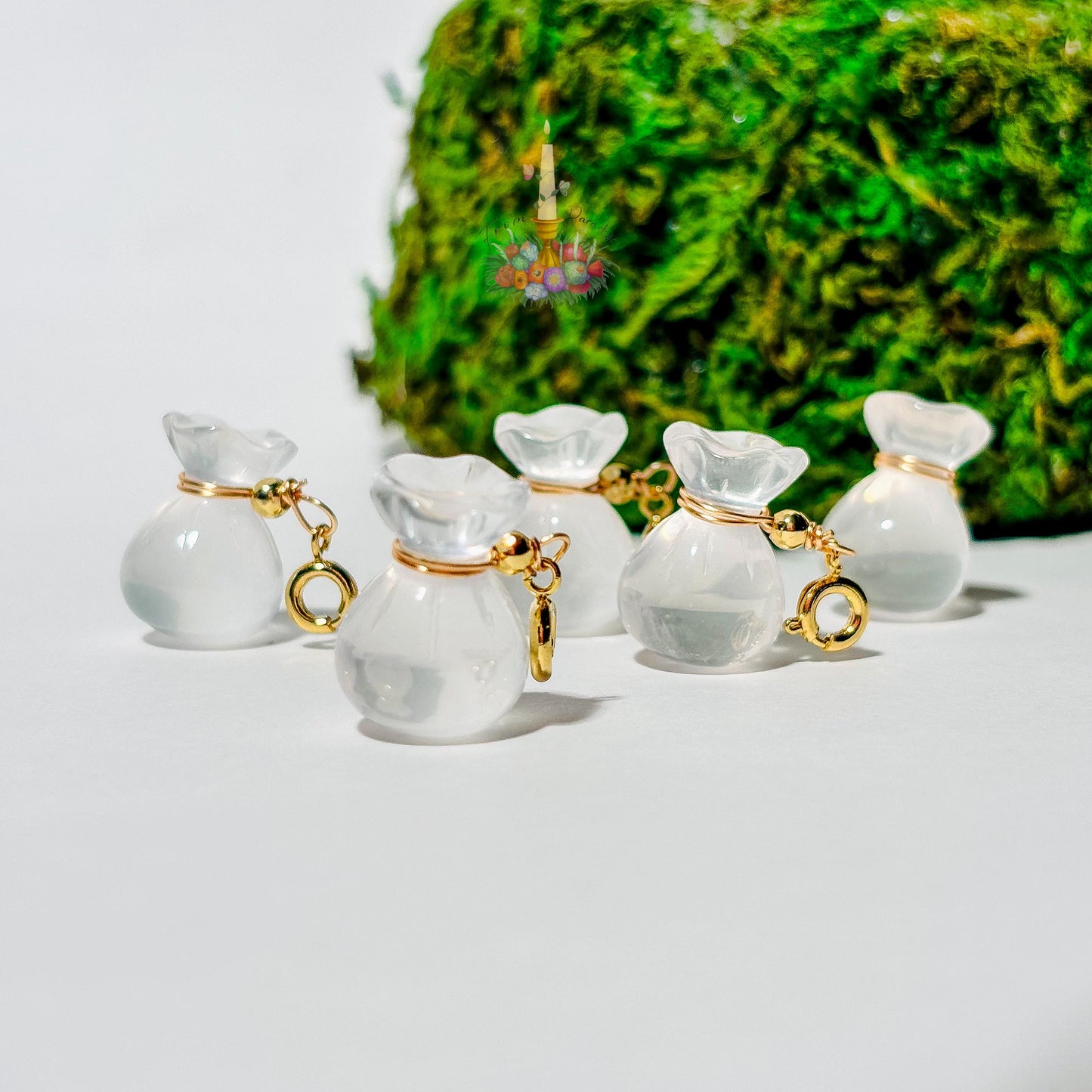 Four mini clear quartz money bag gemstone charms with gold wire wrapping and lobster clasps laid out on a clean white background.