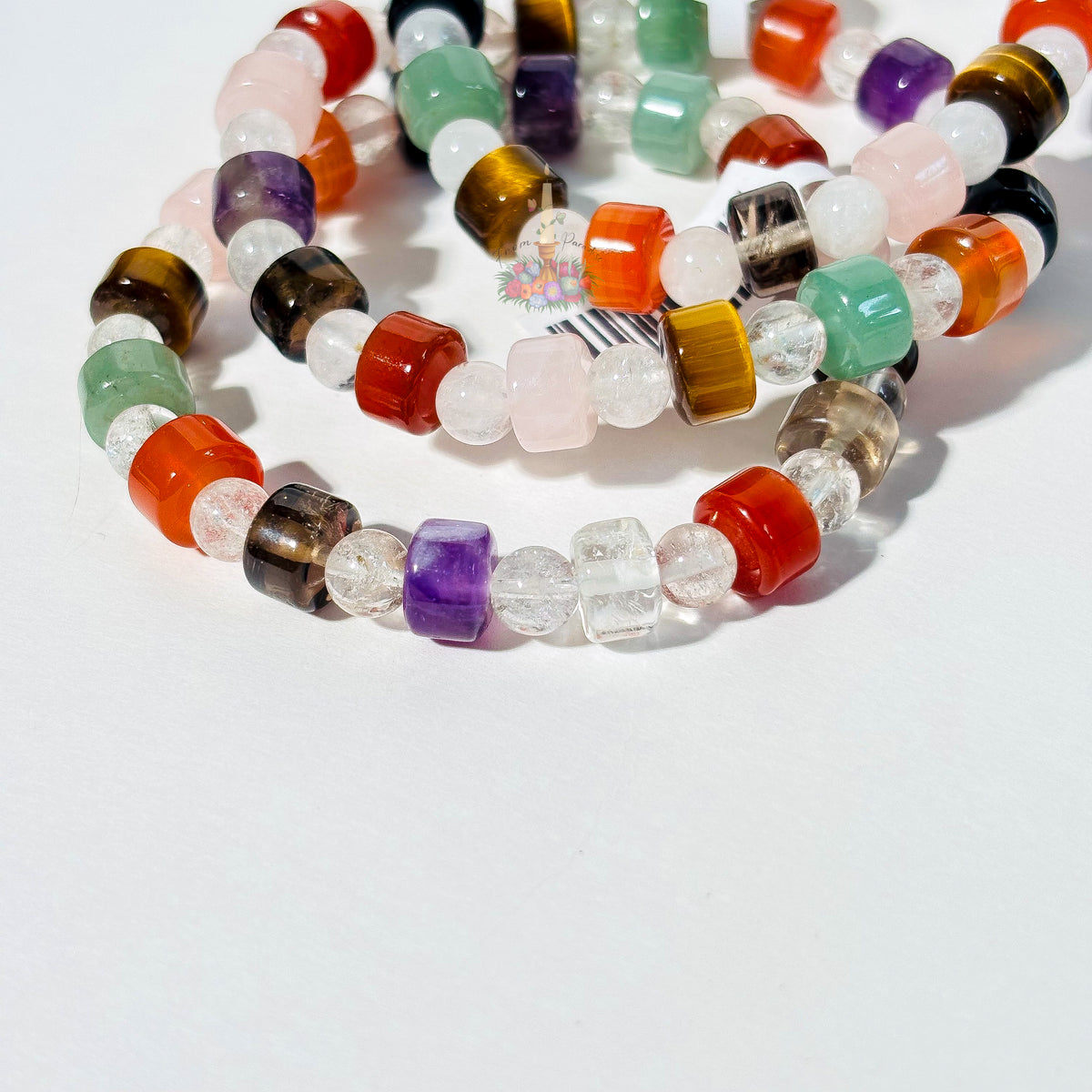 Multi-gemstone crystal bracelets in various colors including amethyst, tiger eye, and rose quartz.
