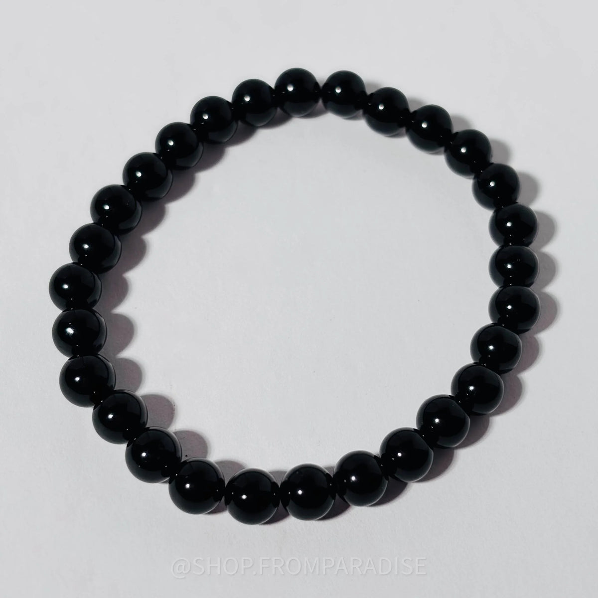 A black beaded stretch bracelet made of glossy, polished round beads, displayed on a light gray background.