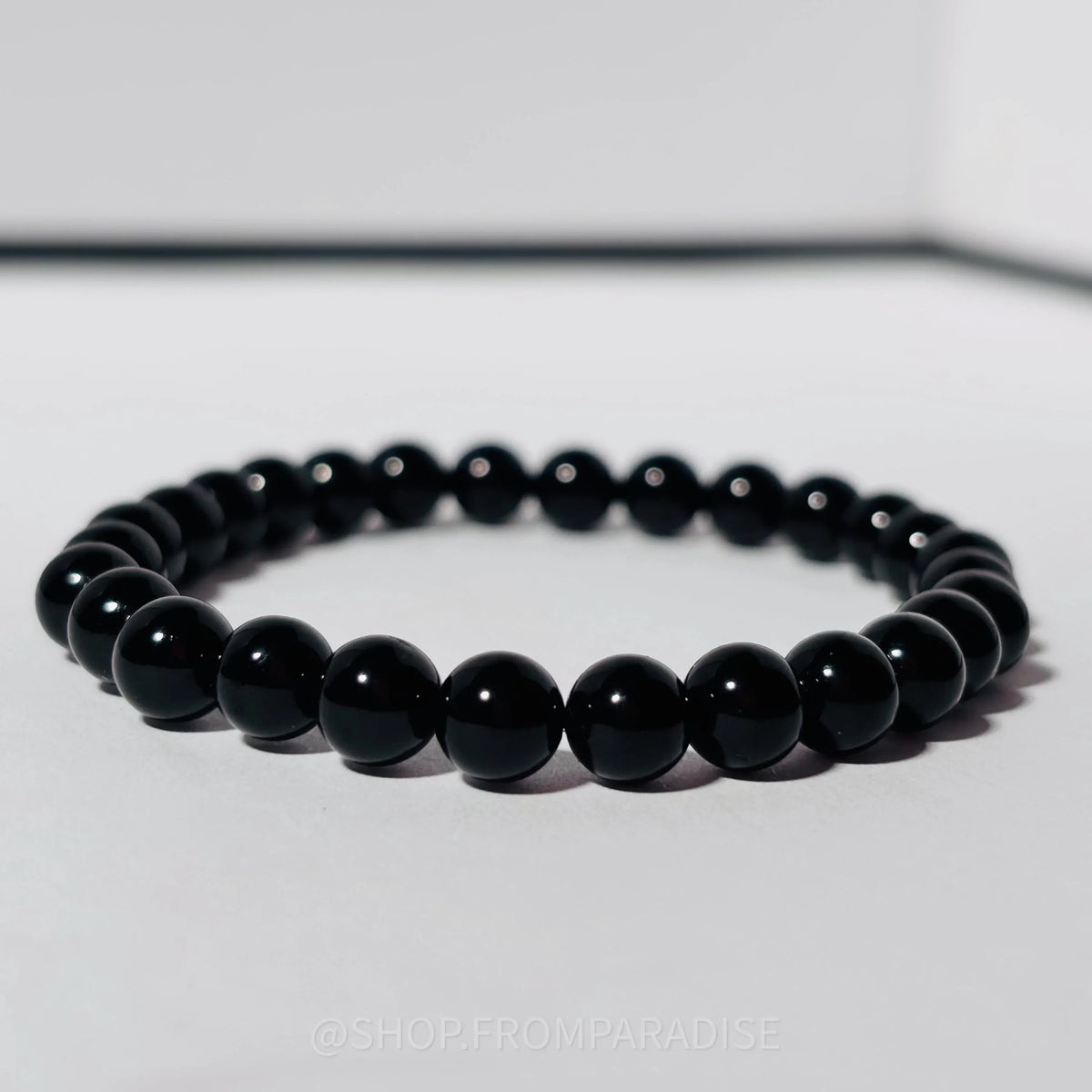 Black beaded bracelet on a light gray background