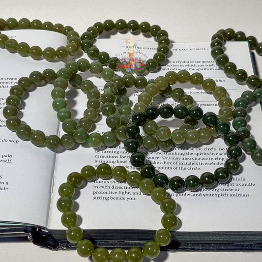 Green stone bead bracelets arranged on an open book, with visible printed text underneath.