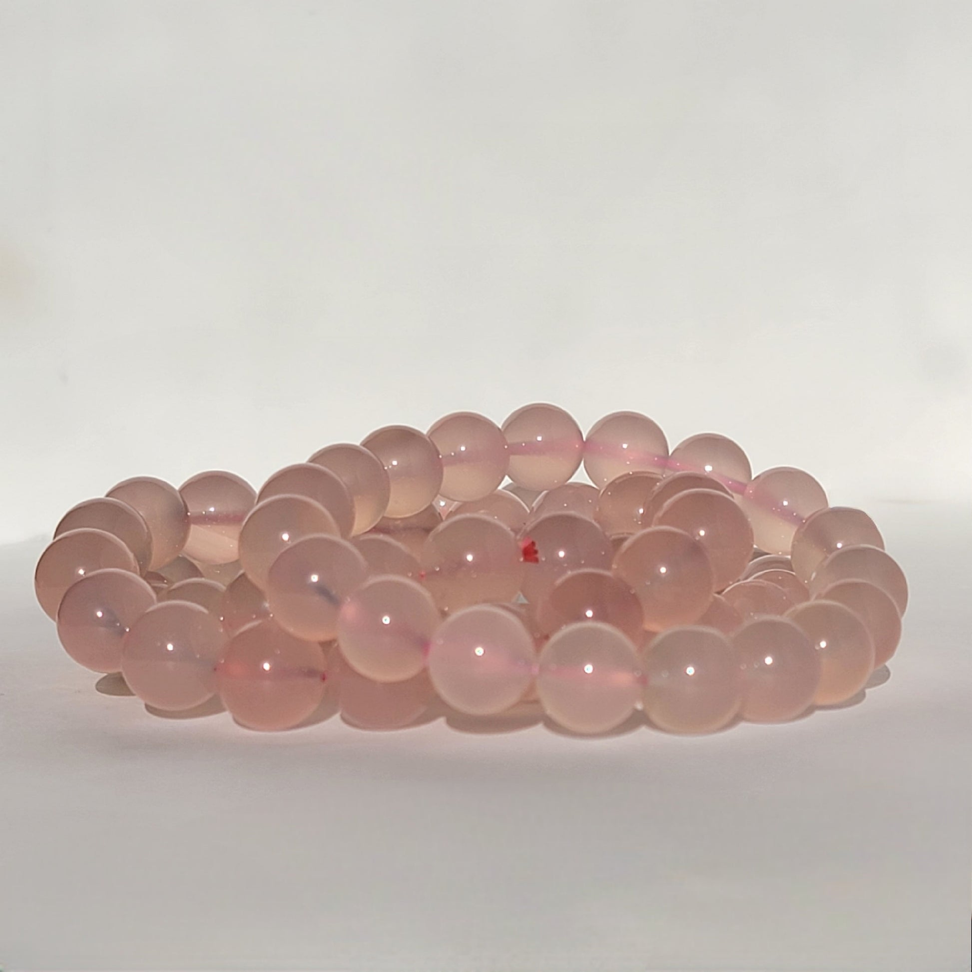 Rose Chalcedony Crystal Bracelet against white background in natural sunlight lighting