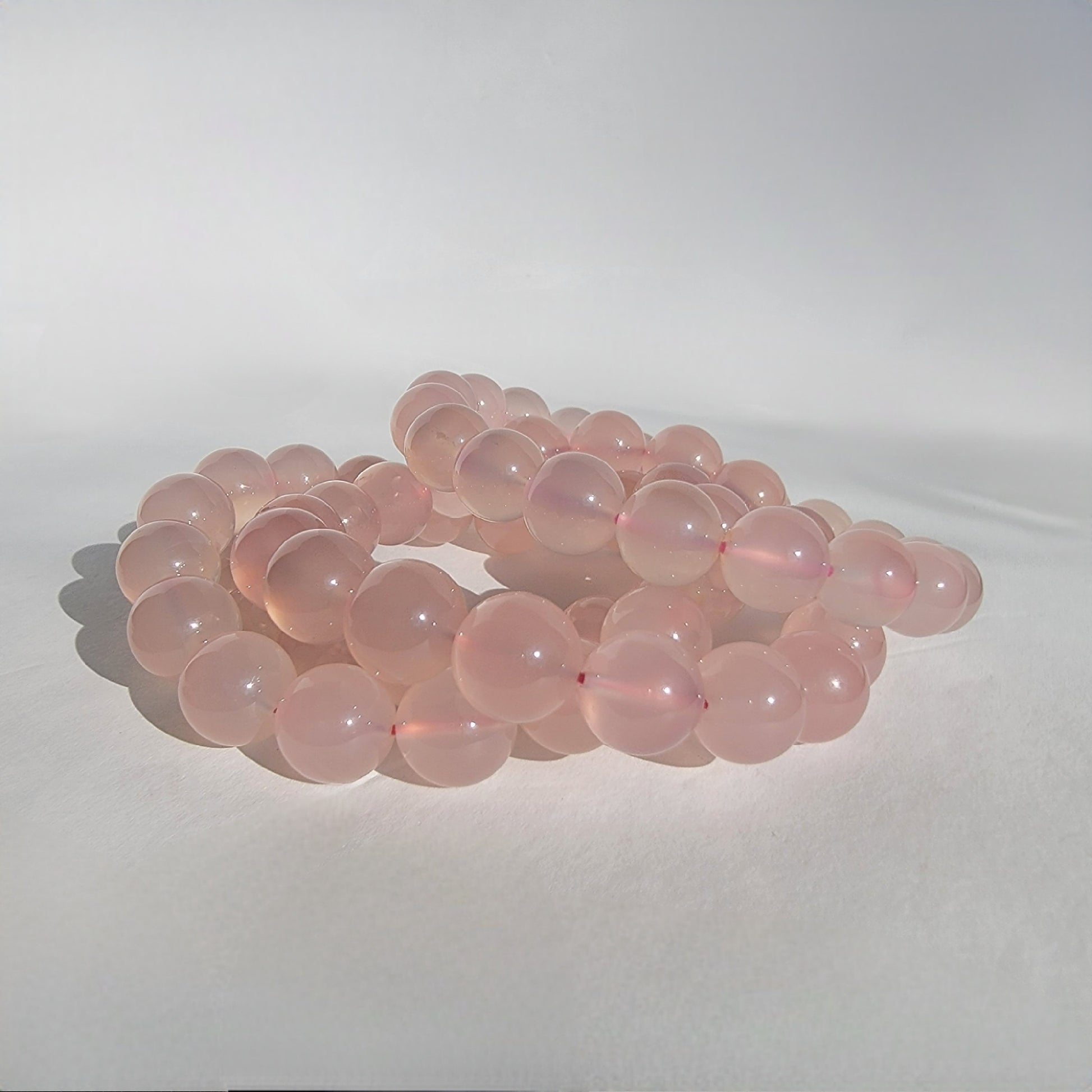Rose Chalcedony Crystal Bracelet against white background in natural sunlight lighting