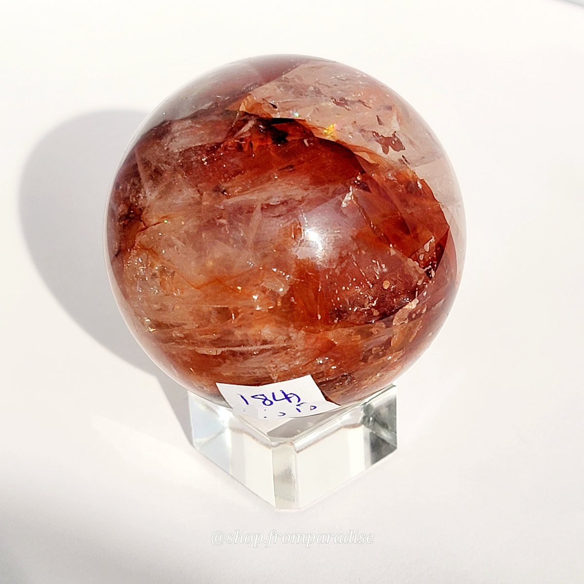 Fire Quartz Red Hematoid Sphere on glass sphere holder against white background