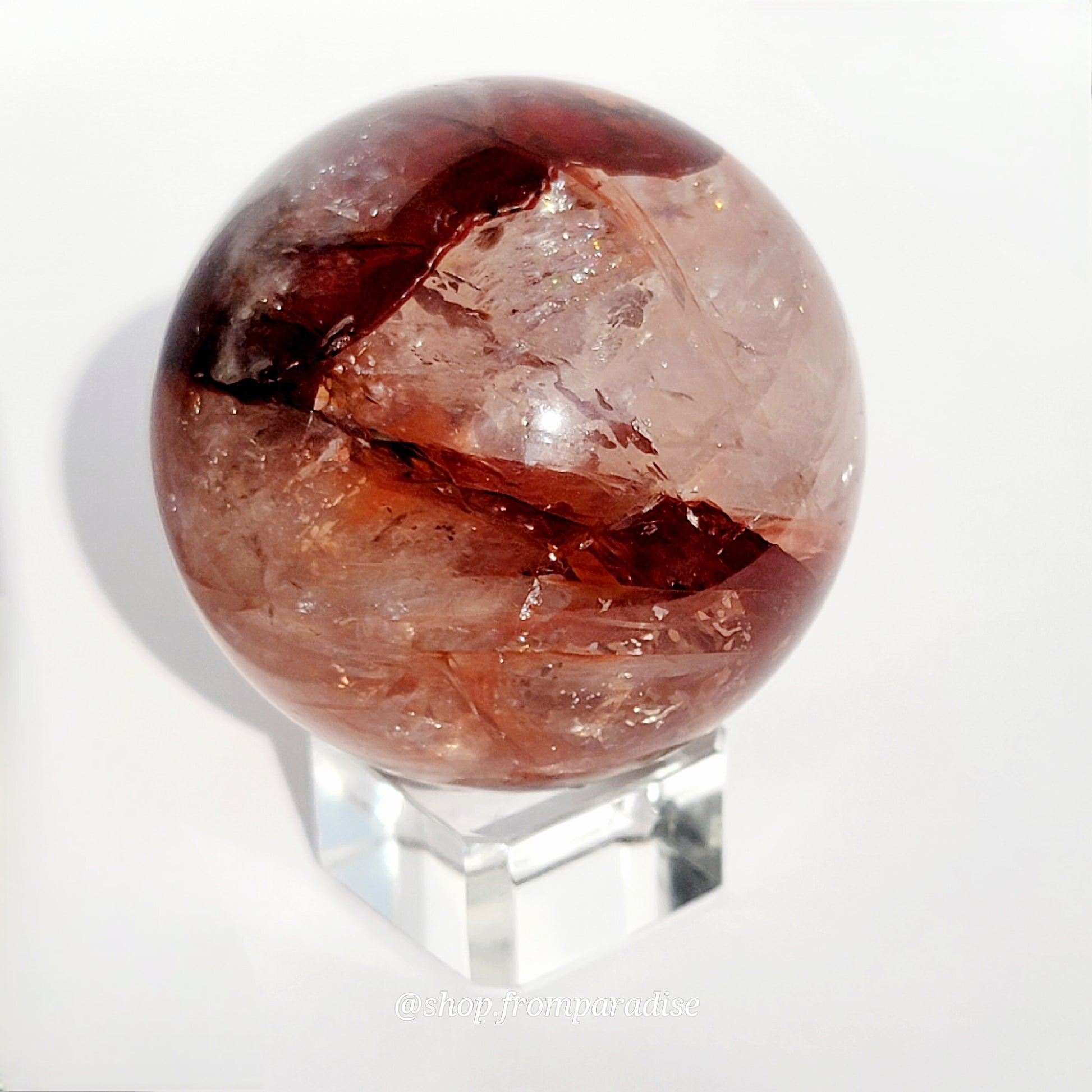 Fire Quartz Red Hematoid Sphere on glass sphere holder against white background