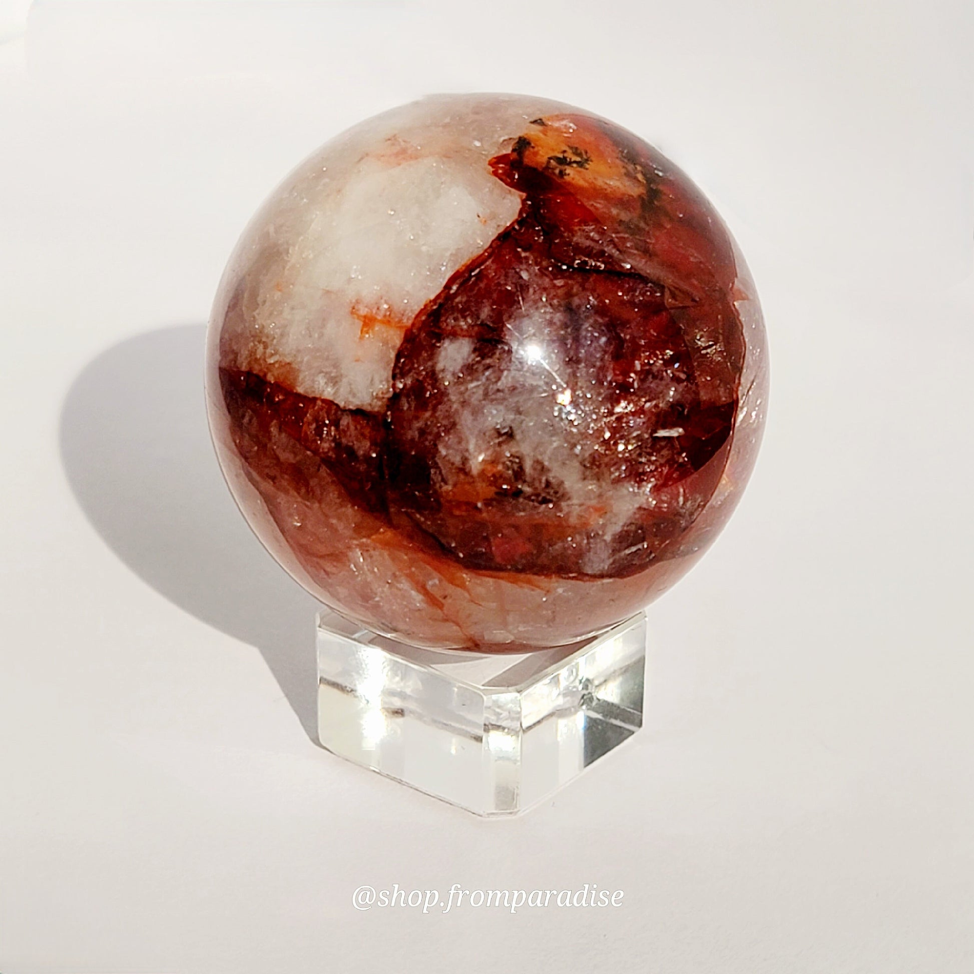 Fire Quartz Red Hematoid Sphere on glass sphere holder against white background