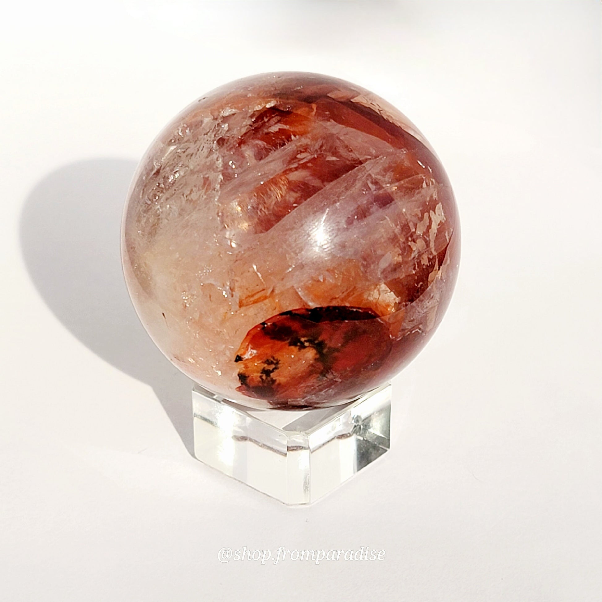 Fire Quartz Red Hematoid Sphere on glass sphere holder against white background