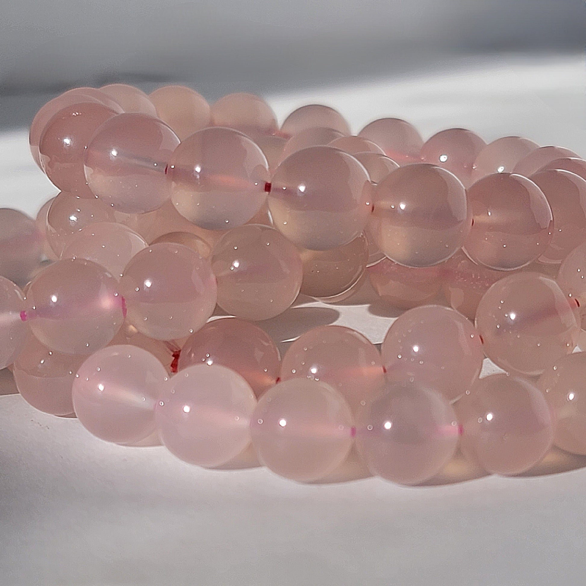 Rose Chalcedony Crystal Bracelet against white background in natural sunlight lighting