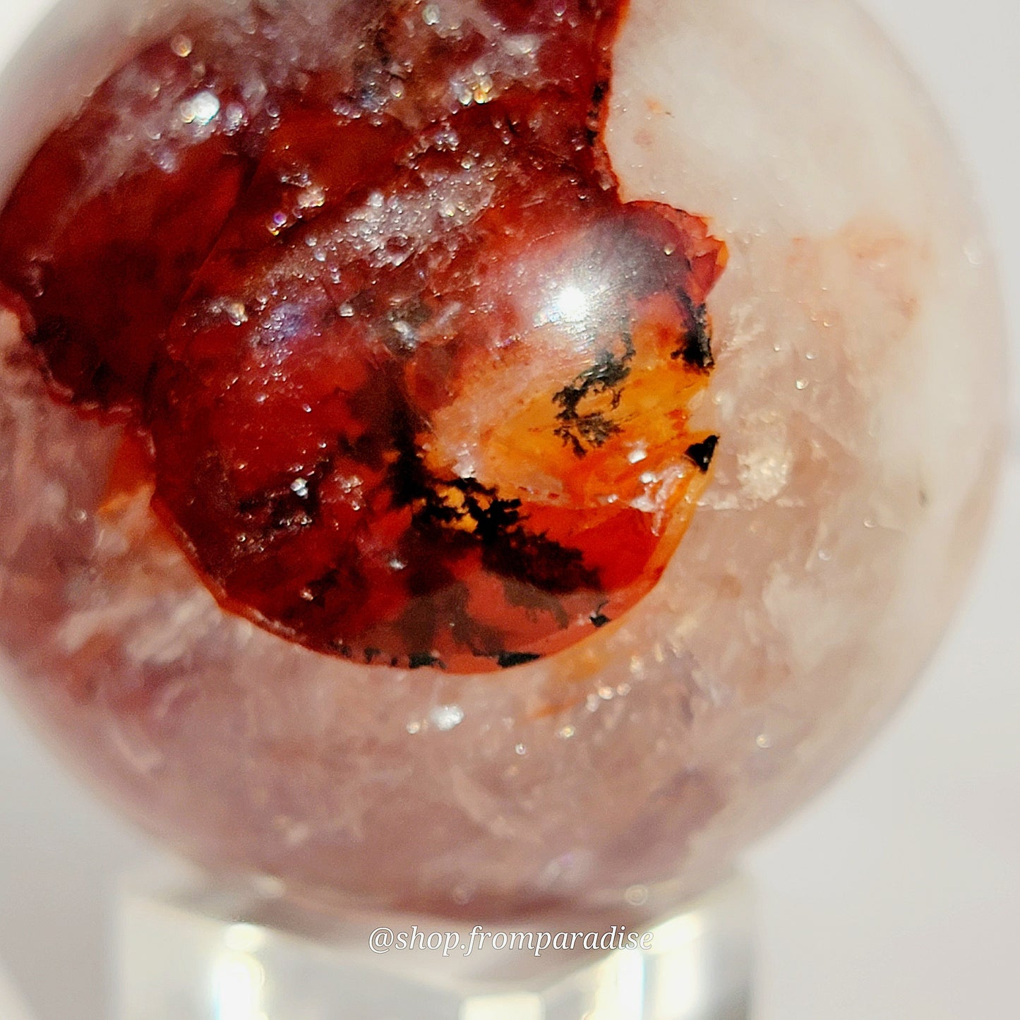 Fire Quartz Red Hematoid Sphere on glass sphere holder against white background