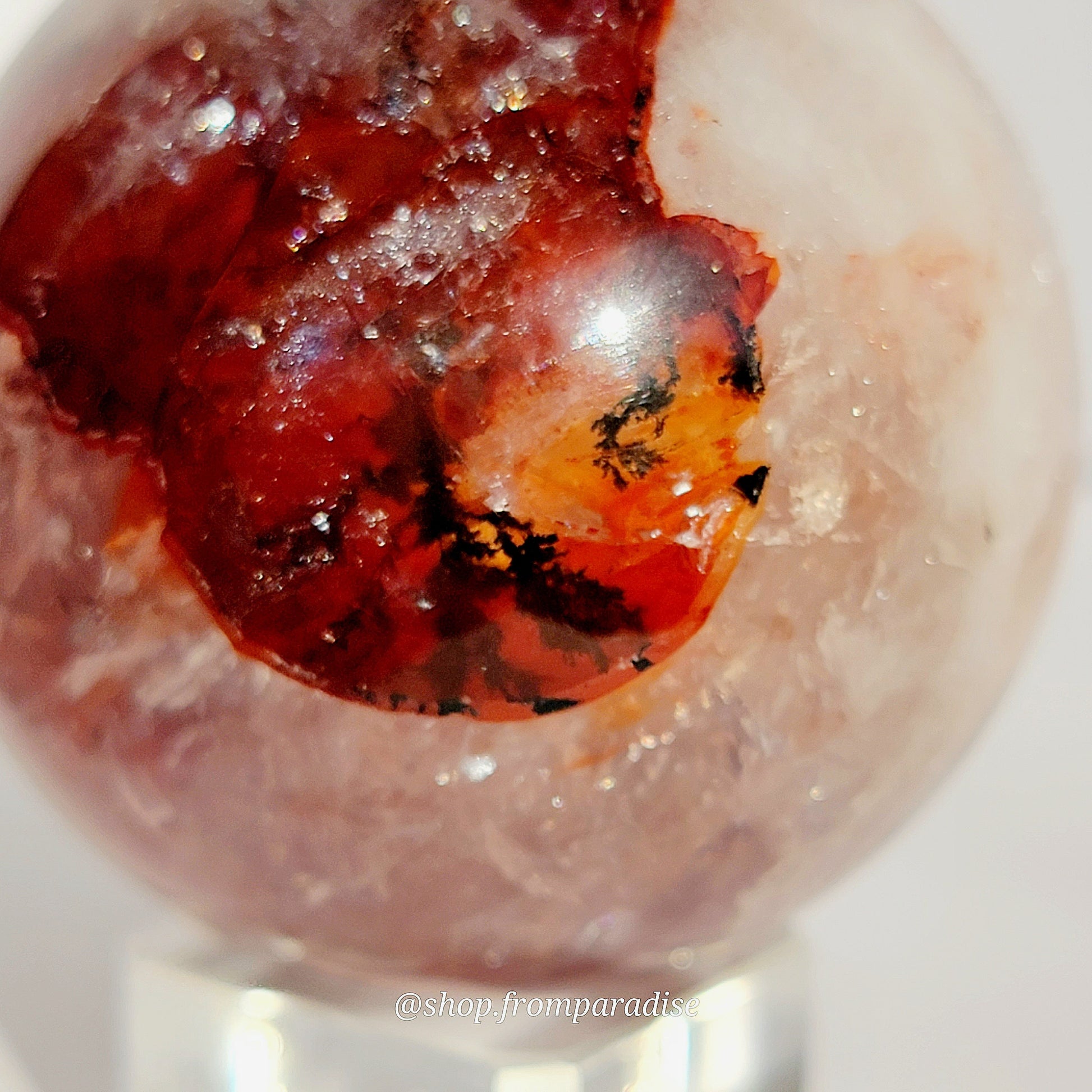 Fire Quartz Red Hematoid Sphere on glass sphere holder against white background