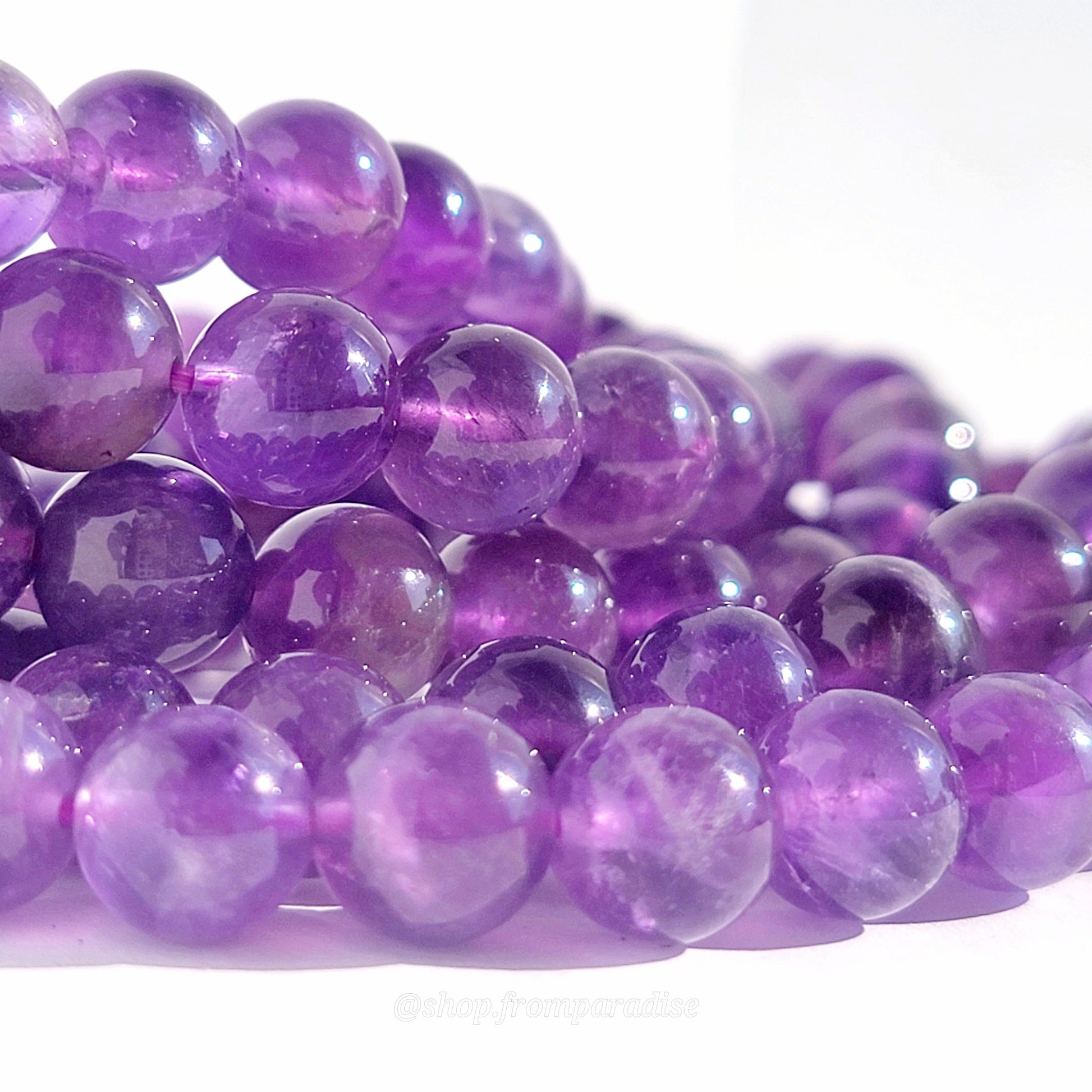 closeup of amethyst bracelet beads against a white background