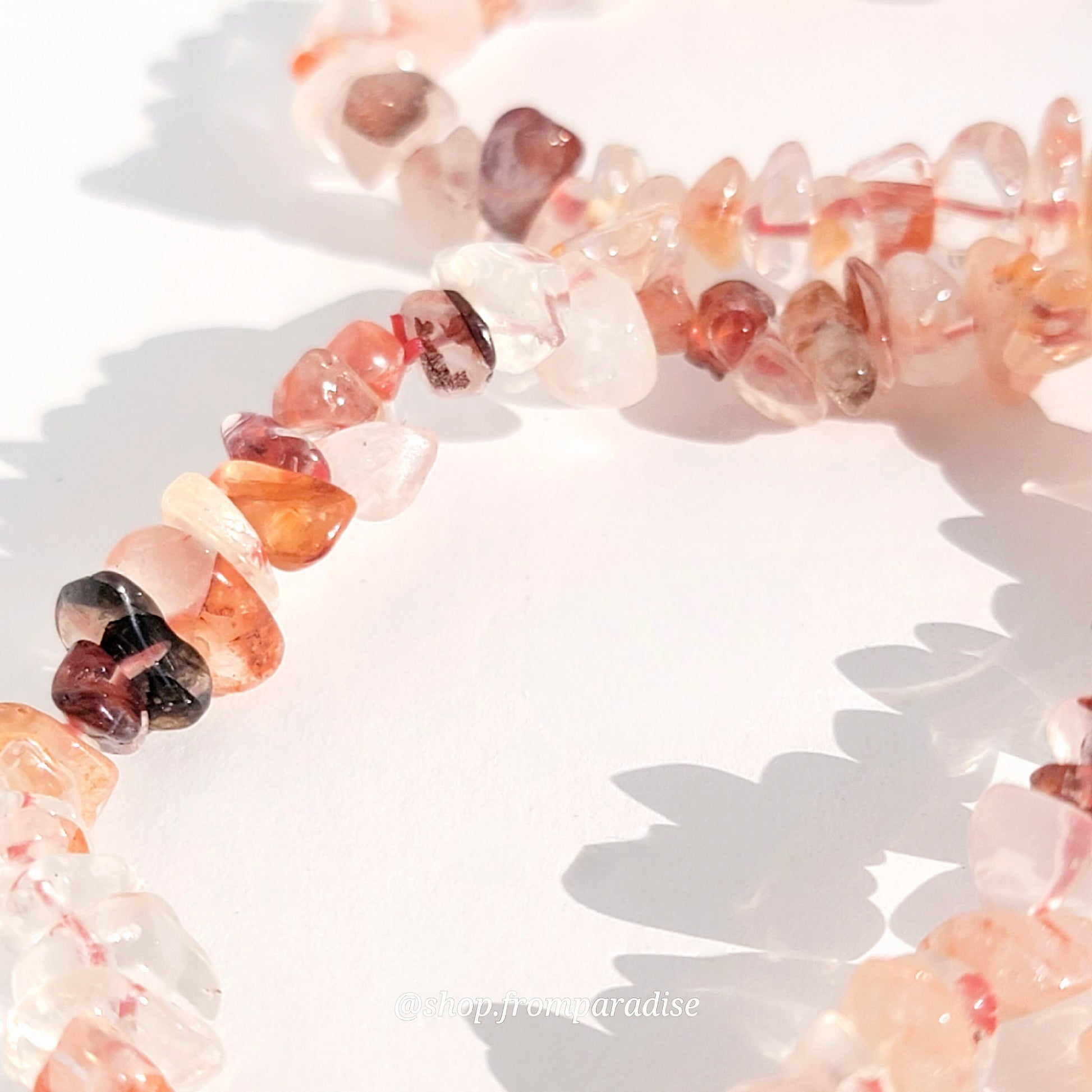 closeup of fire quartz crystal chip stretch bracelet jewelry displayed against a white background