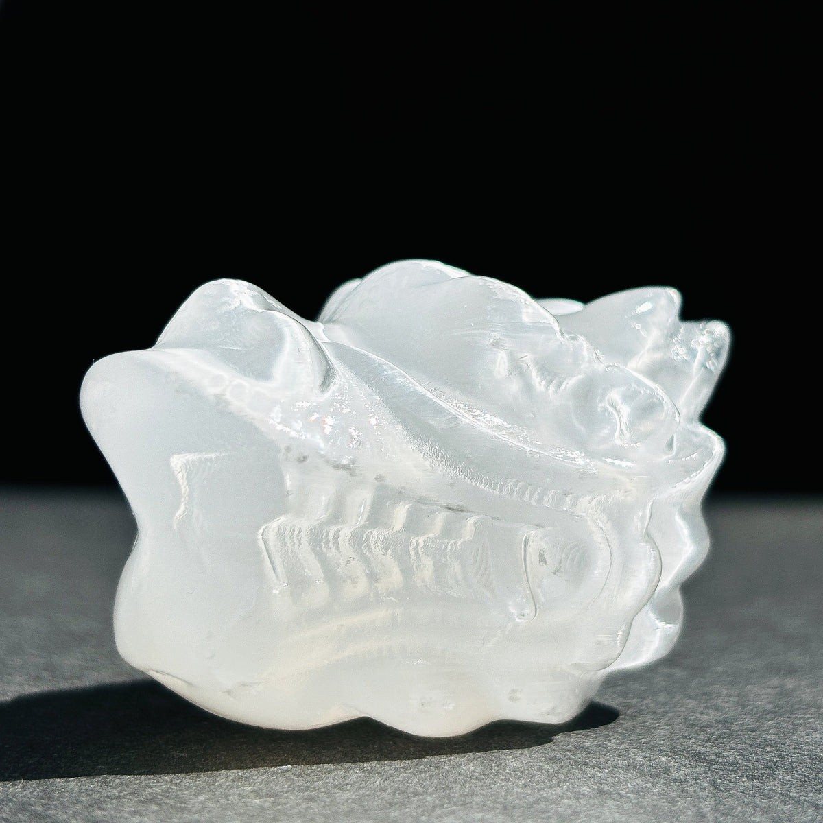 Selenite Oriental Dragon Crystal Sculpture against a black background