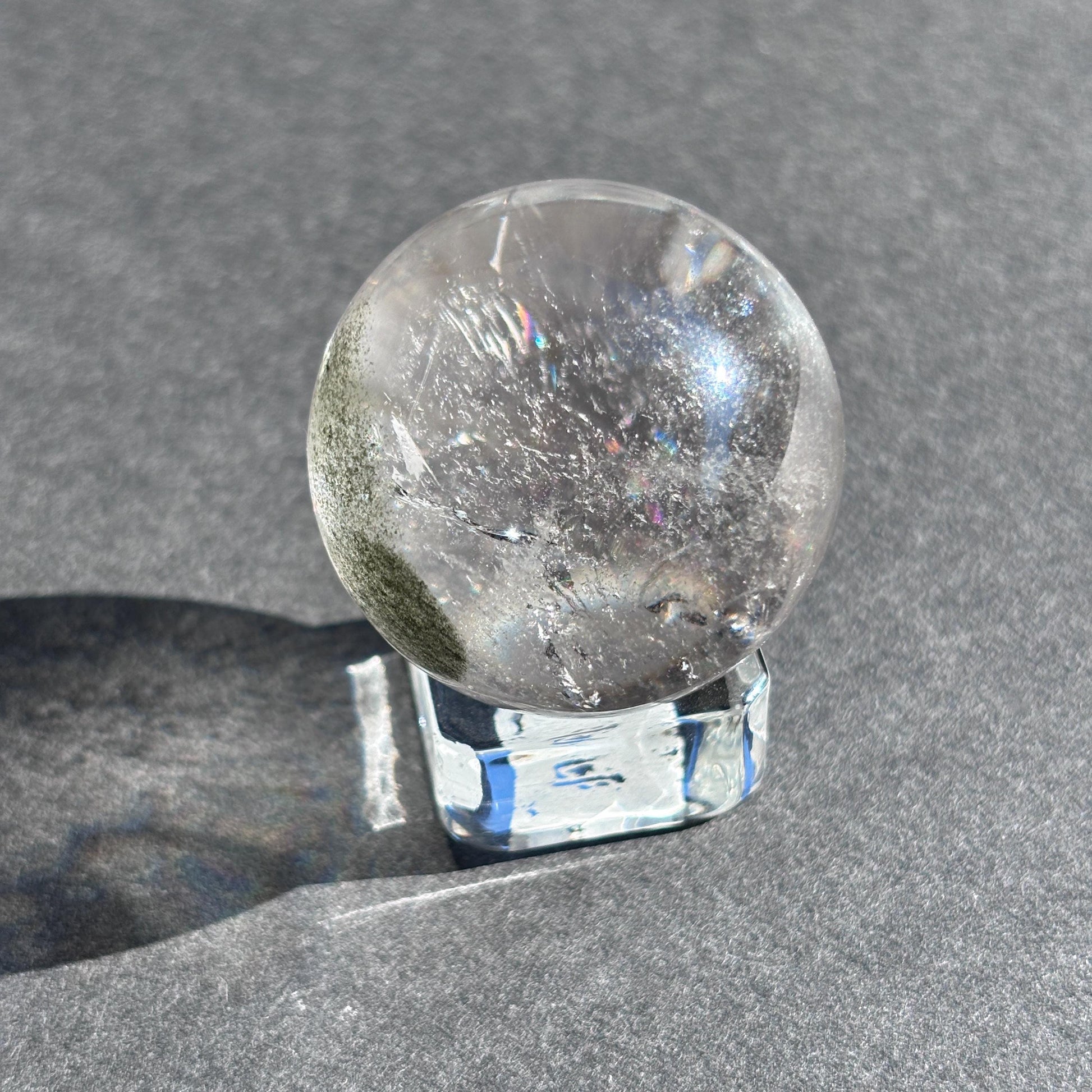 Clear Quartz with Chloride Crystal Sphere against a black background on a glass sphere holder