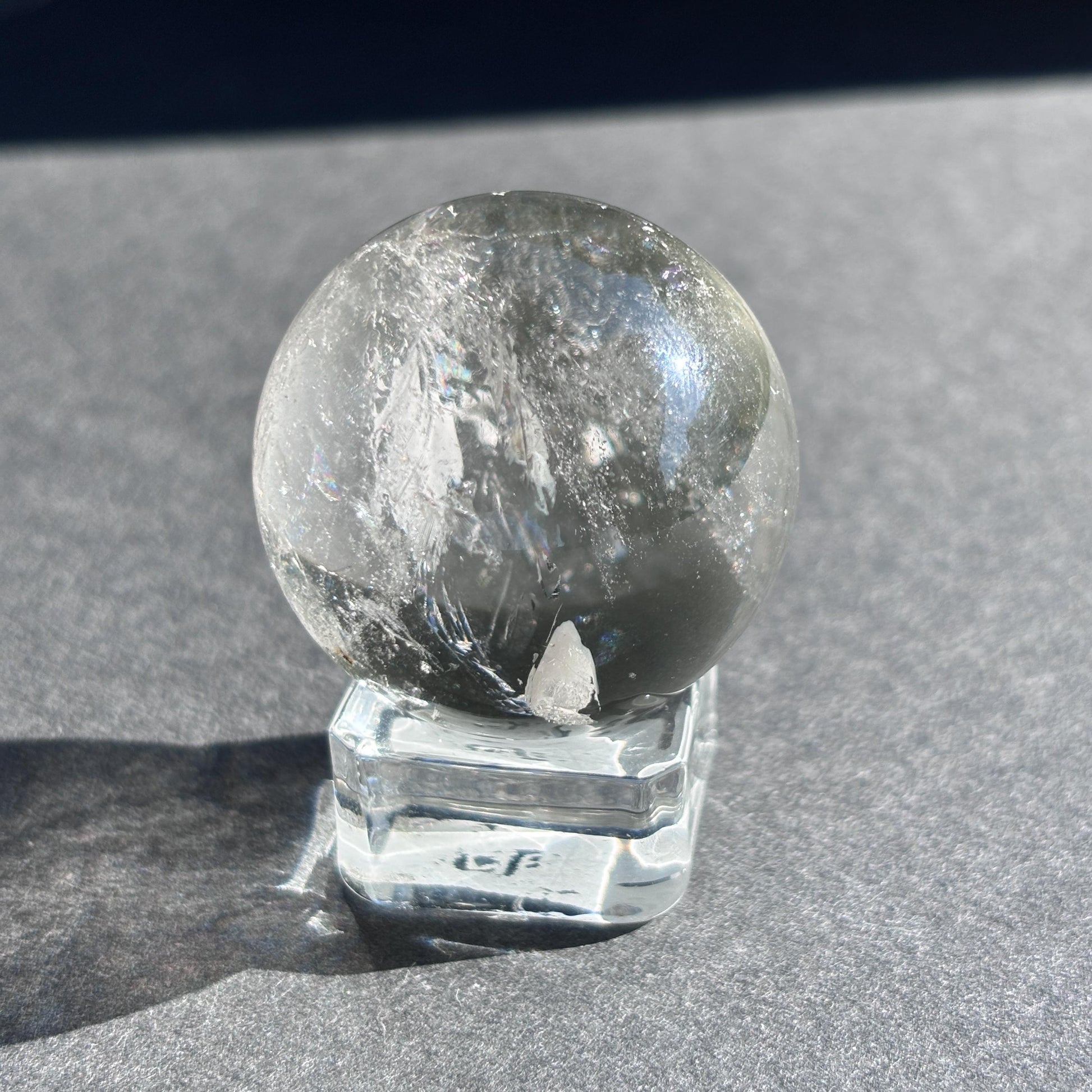 Clear Quartz with Chloride Crystal Sphere against a black background on a glass sphere holder