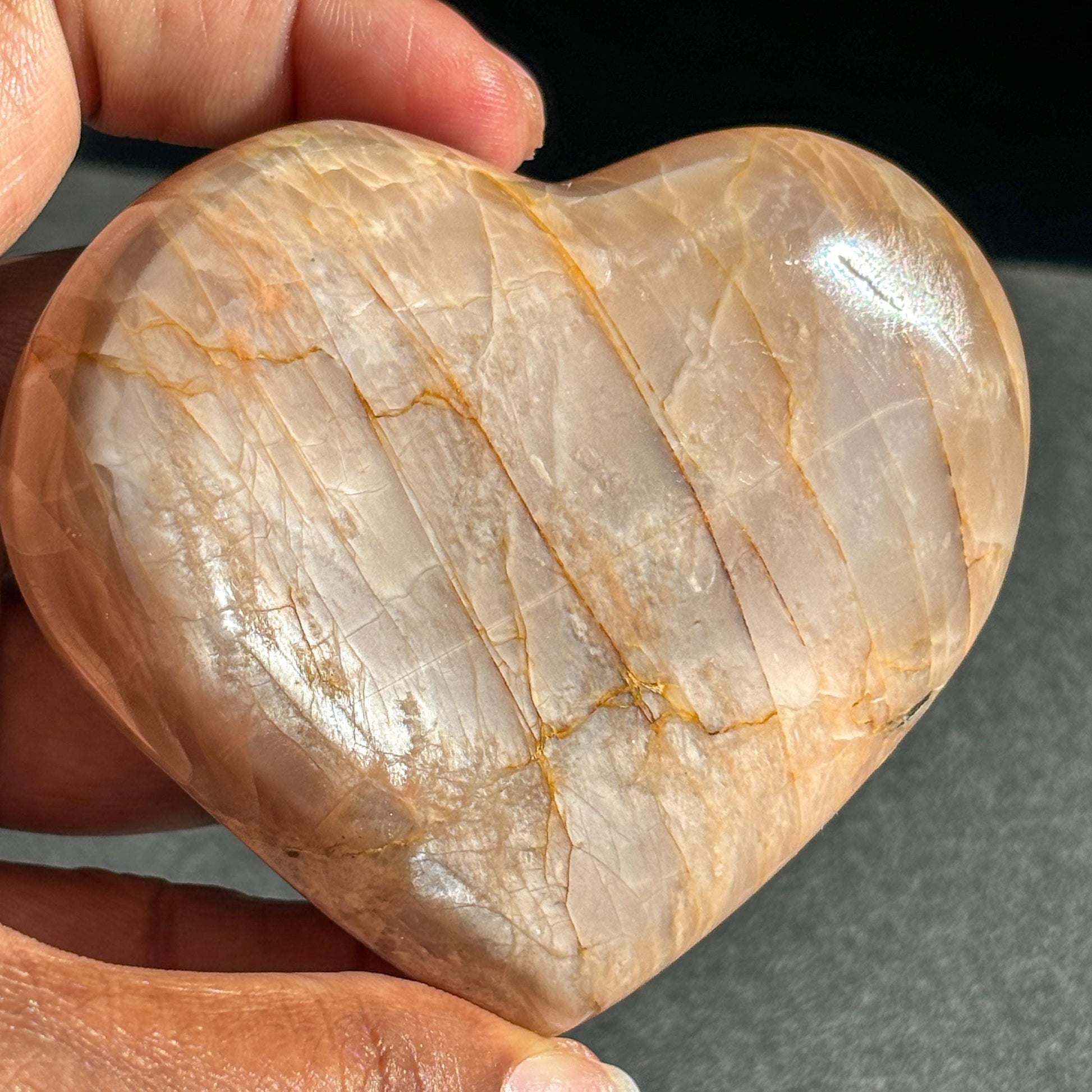 Peach Moonstone Heart Crystal Sculpture against a black background