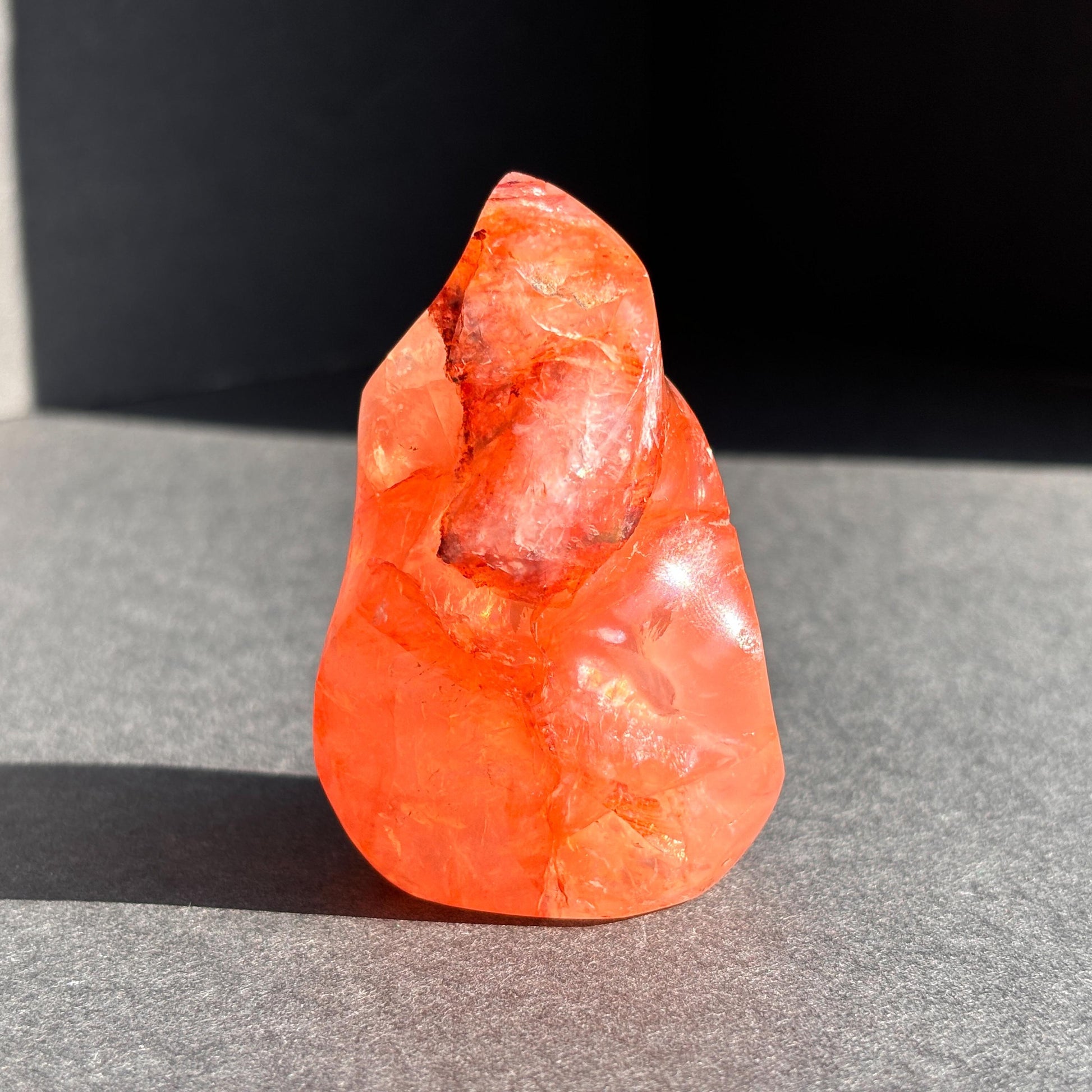 Fire Quartz Red Hematoid Crystal Flame Sculpture against a black background