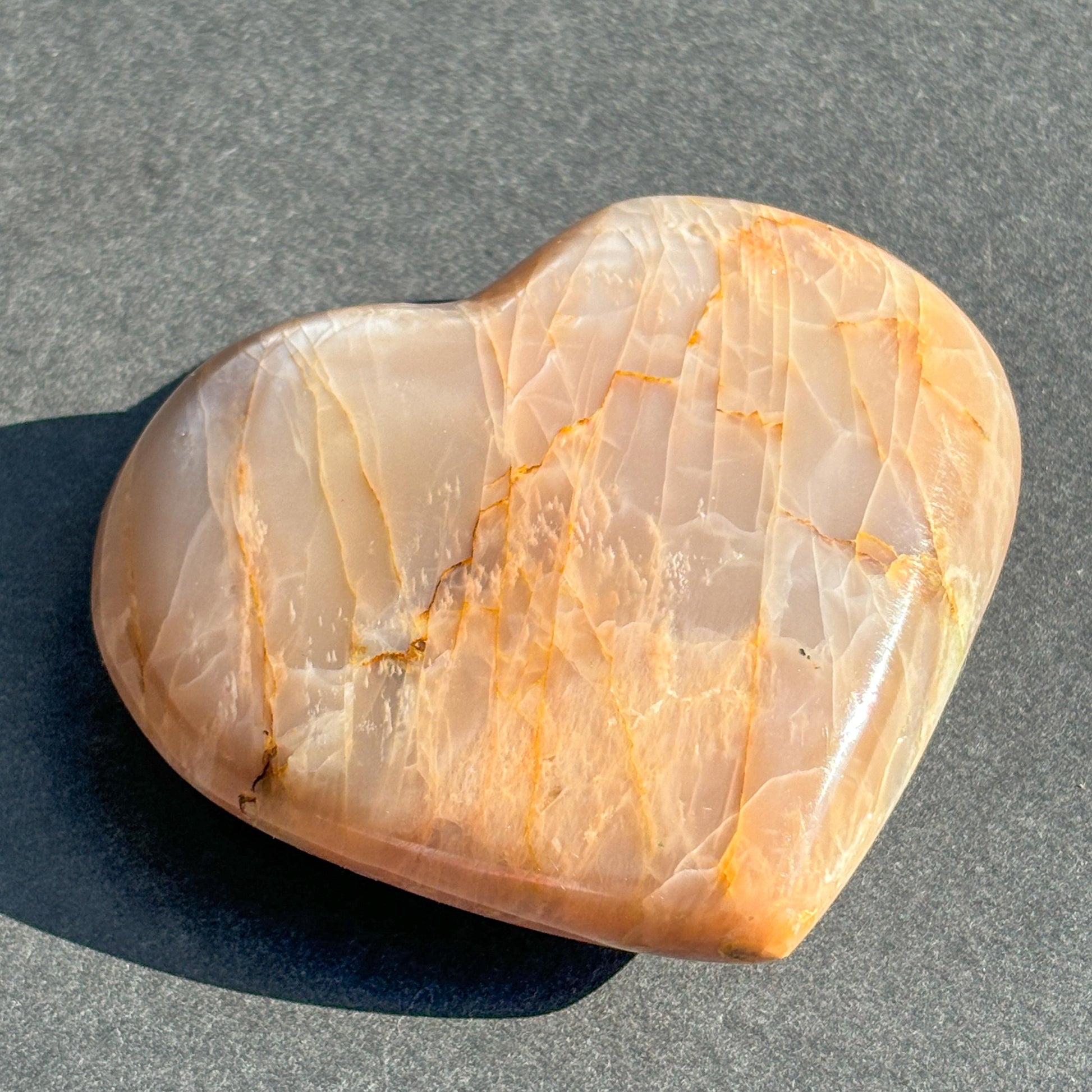 Peach Moonstone Heart Crystal Sculpture against a black background