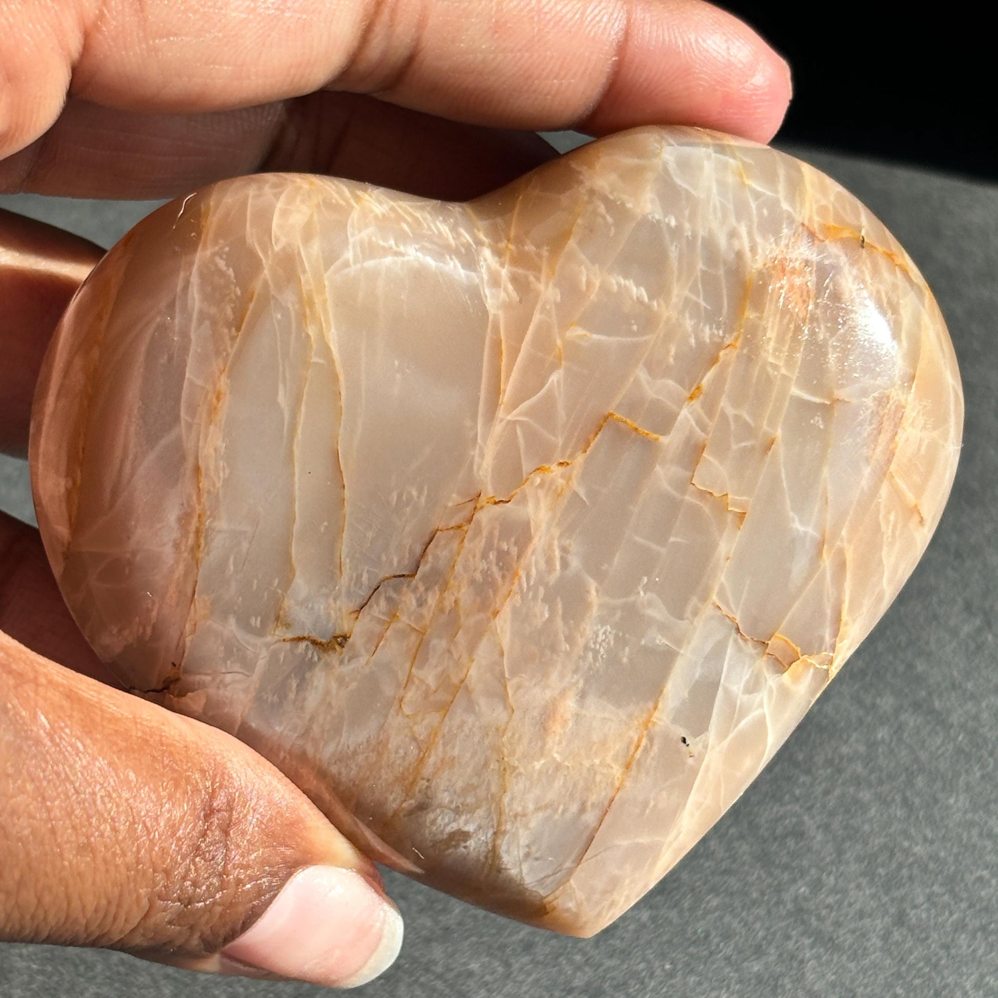 Peach Moonstone Heart Crystal Sculpture against a black background