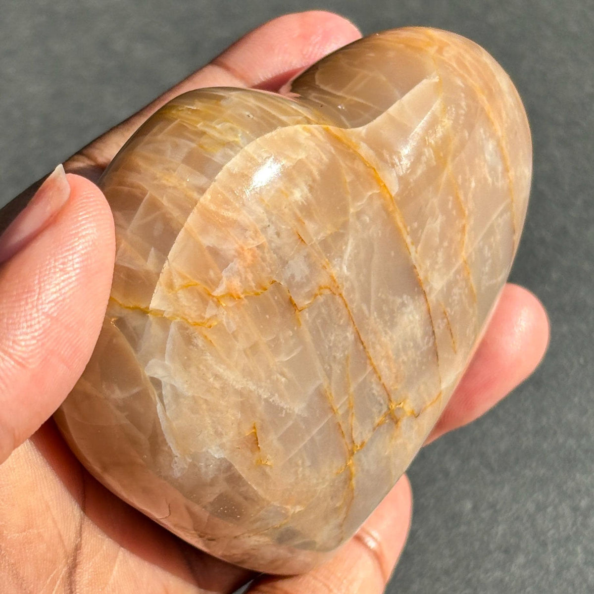 Peach Moonstone Heart Crystal Sculpture against a black background