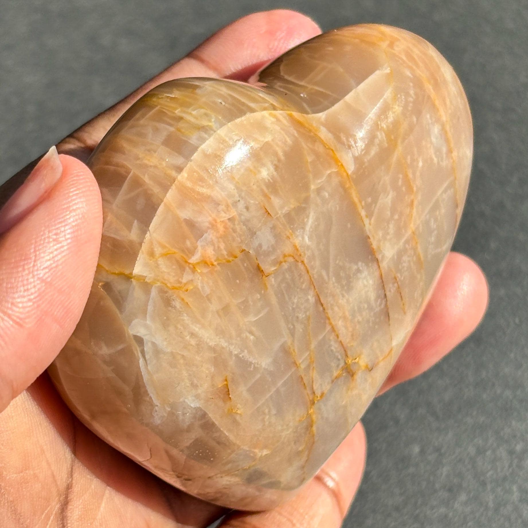 Peach Moonstone Heart Crystal Sculpture against a black background
