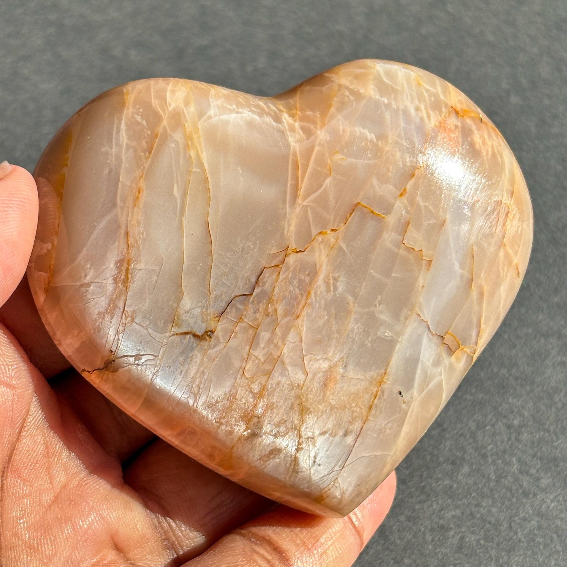 Peach Moonstone Heart Crystal Sculpture against a black background