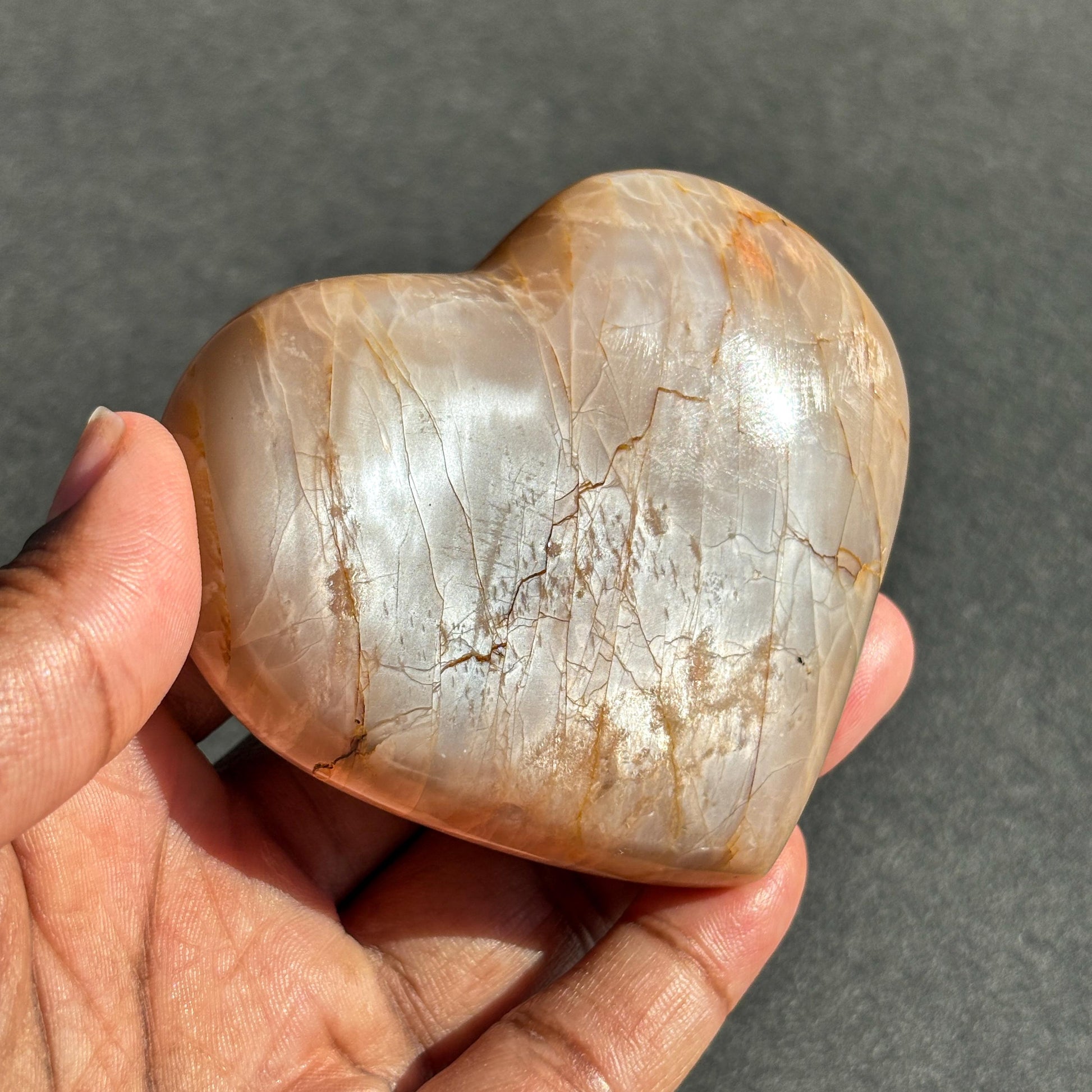 Peach Moonstone Heart Crystal Sculpture against a black background