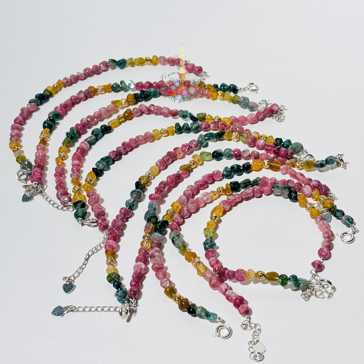Handmade gemstone bracelet made with multi-colored tourmaline chip beads in shades of pink, yellow, teal, and green, accented with gold textured spacer beads and a silver adjustable clasp chain.