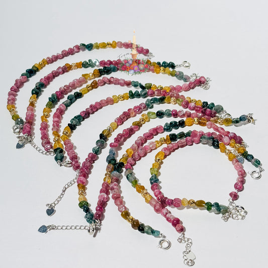 Handmade gemstone bracelet made with multi-colored tourmaline chip beads in shades of pink, yellow, teal, and green, accented with gold textured spacer beads and a silver adjustable clasp chain.