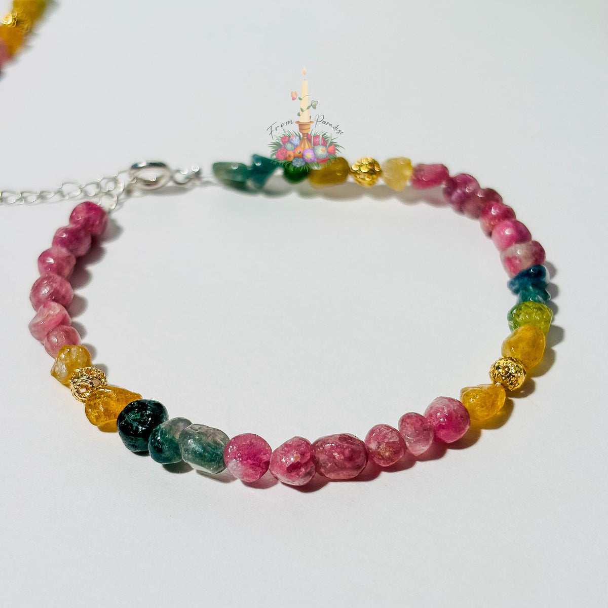 Handmade gemstone bracelet made with multi-colored tourmaline chip beads in shades of pink, yellow, teal, and green, accented with gold textured spacer beads and a silver adjustable clasp chain.