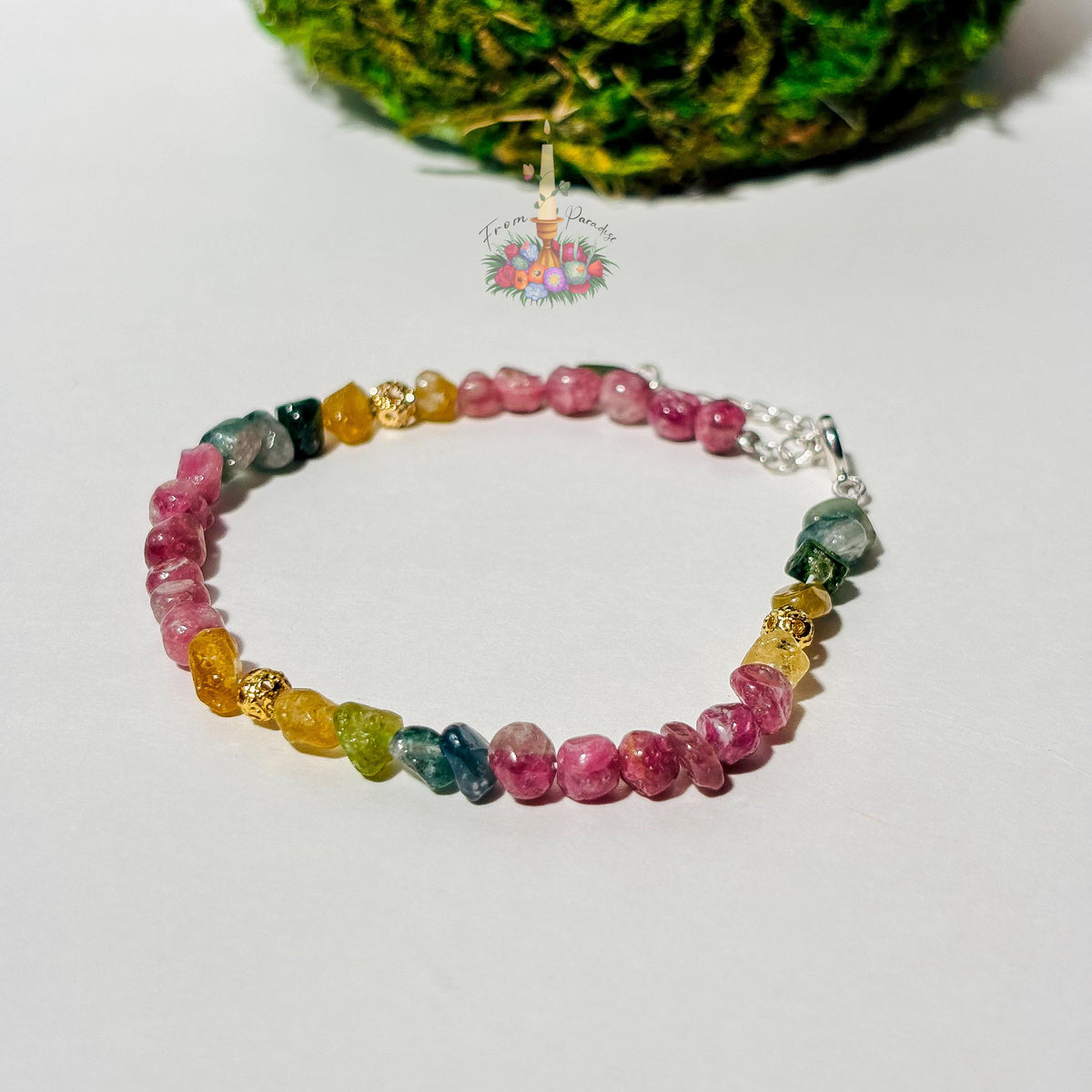 Handmade gemstone bracelet made with multi-colored tourmaline chip beads in shades of pink, yellow, teal, and green, accented with gold textured spacer beads and a silver adjustable clasp chain.