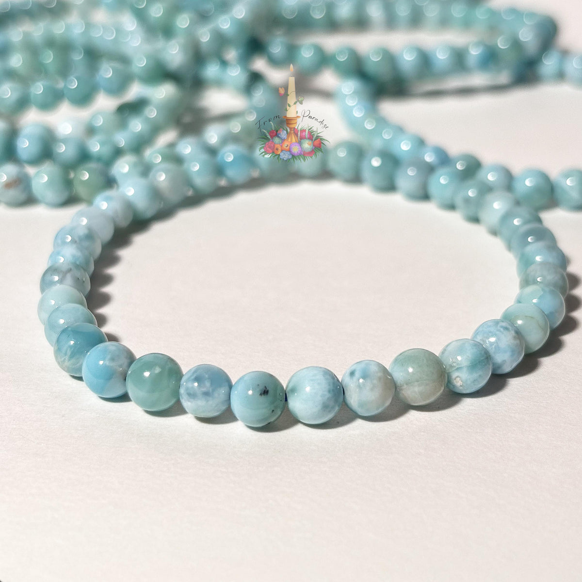 Stack of natural light blue and white Larimar beaded stretch bracelets on a white background, highlighting the gemstone's ocean-like patterns.