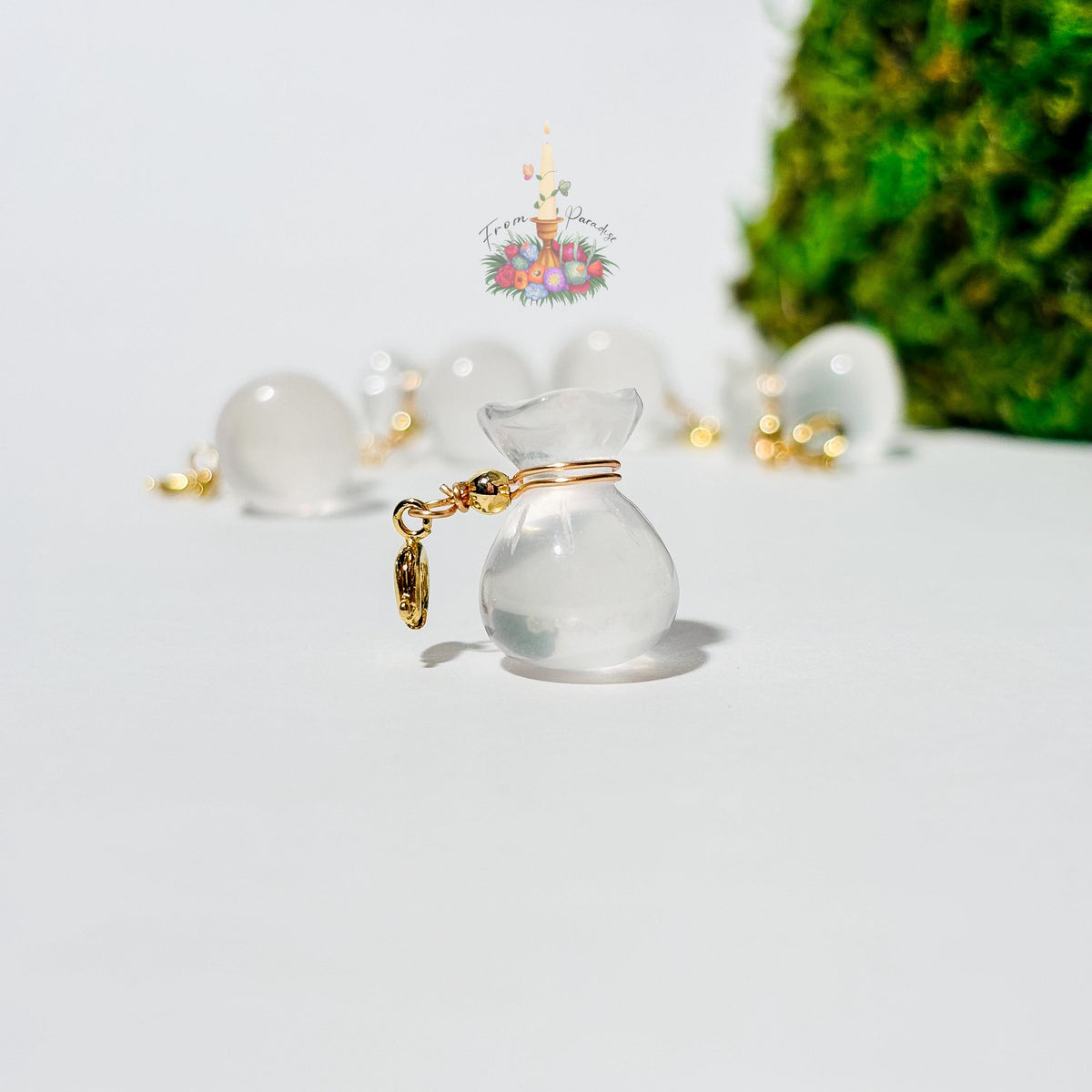 Four mini clear quartz money bag gemstone charms with gold wire wrapping and lobster clasps laid out on a clean white background.