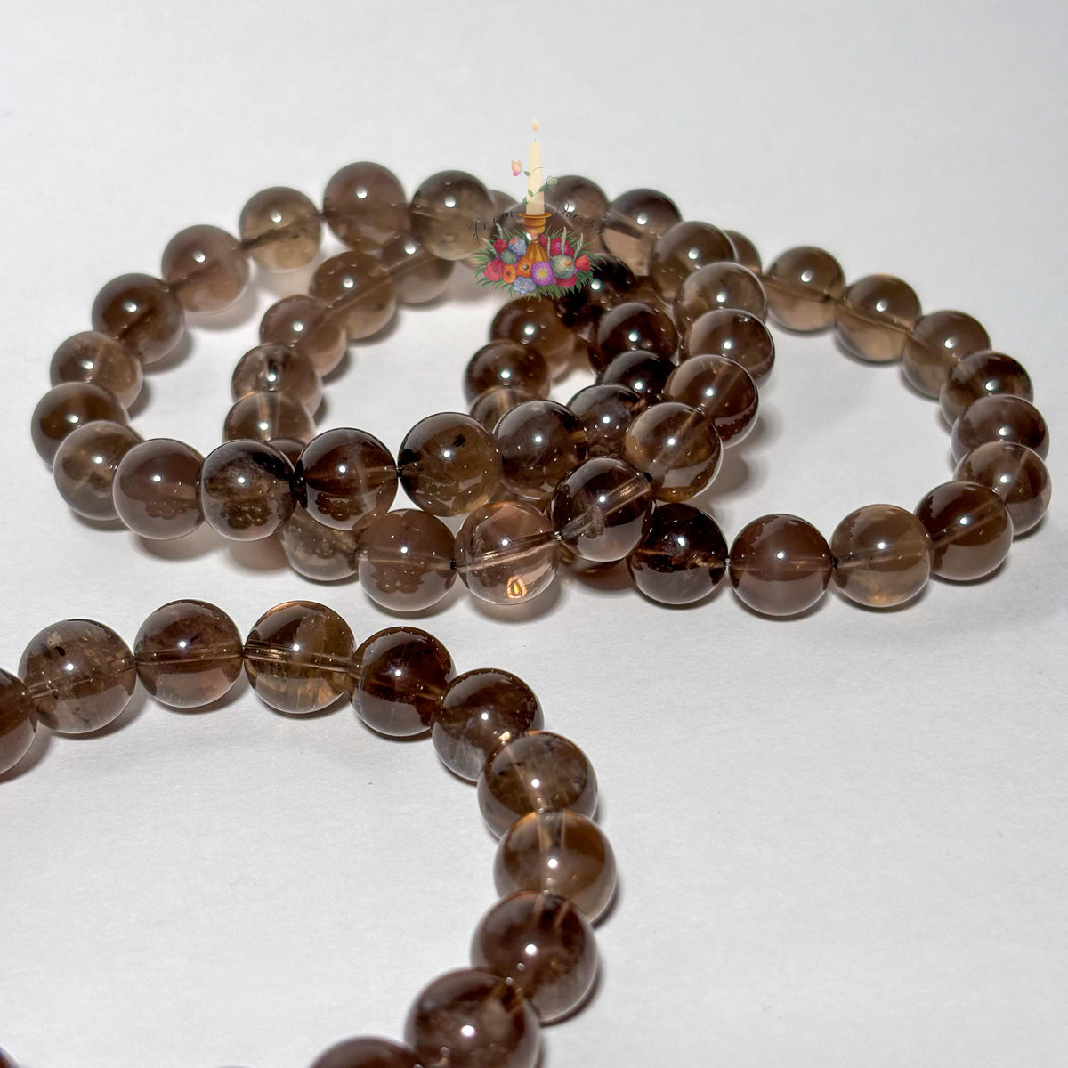 A strand of smooth, translucent brown gemstone beads arranged in loose loops on a plain white background.